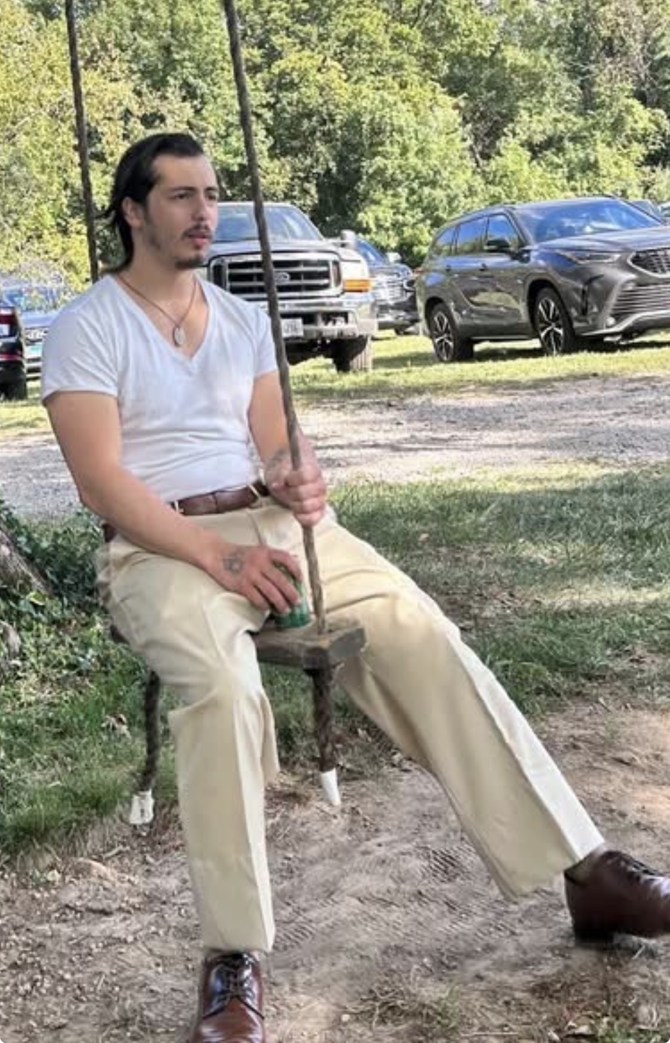 Marcos Zuniga sitting on a rope swing under a tree, looking off-camera